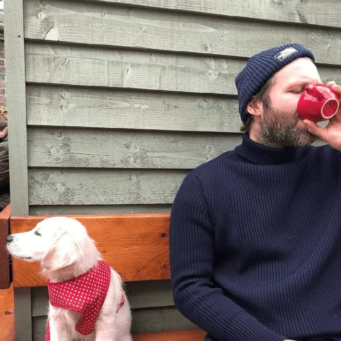 Man drinking coffee with his dog beside him in dog friendly cafe in Melbourne
