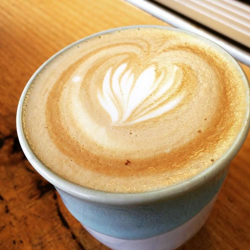 Cup of coffee on a wooden table from a dog friendly cafe in Melbourne
