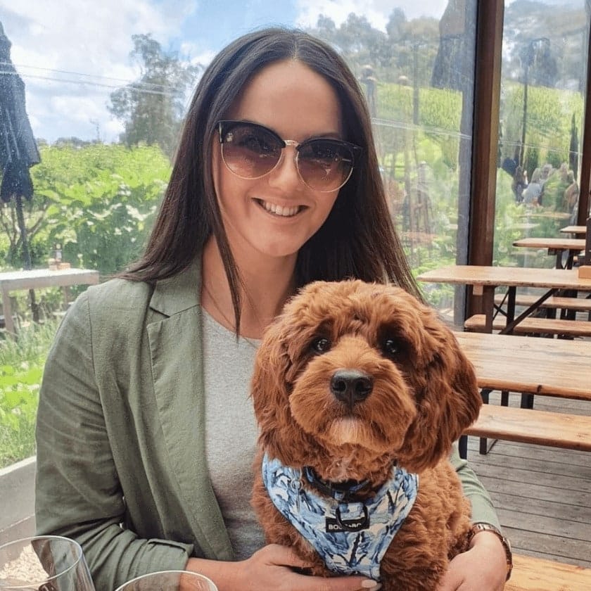 Woman smiling for the camera with her dog in one of the outdoor seats of this pet friendly cafe in Melbourne