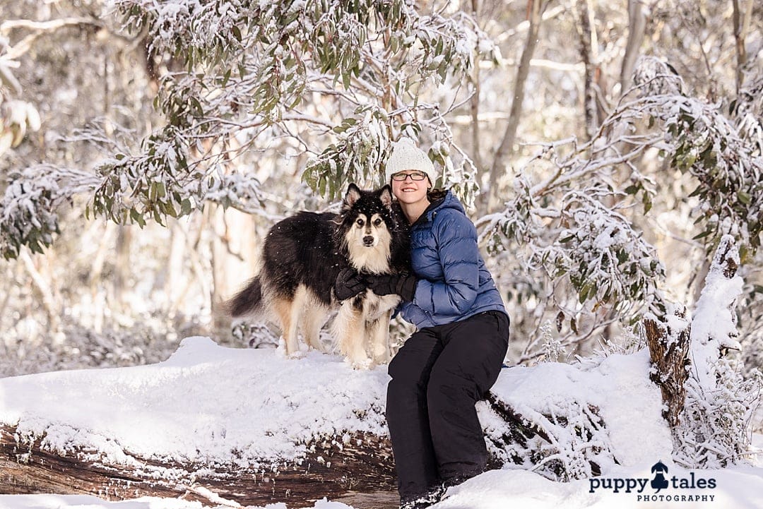 Jaska, the Finnish Lapphund, and his proud fur mom pose for a photo in the snow, with a big grin on her face in a beautiful snowy background.